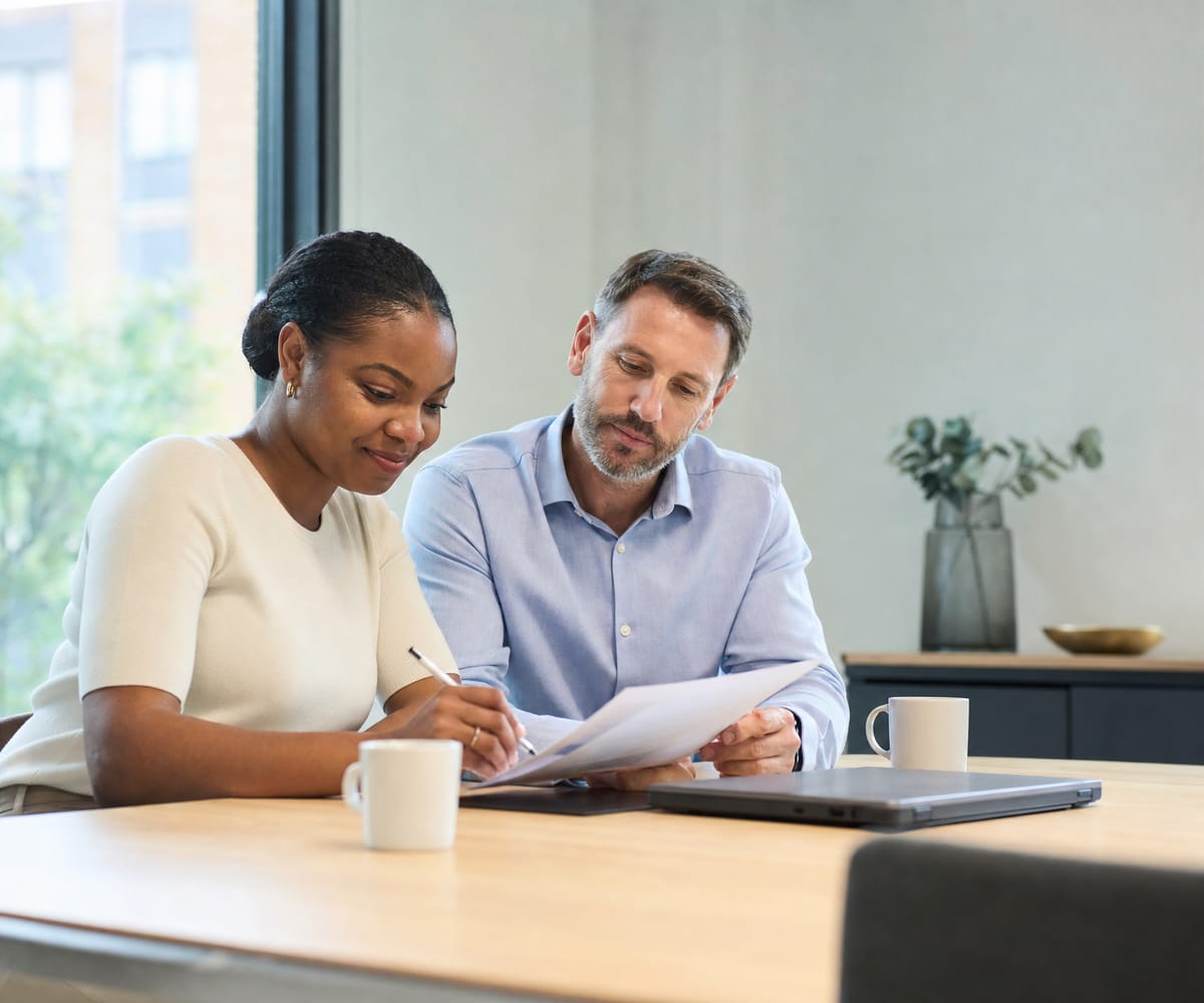Two colleagues reviewing a printed report together at a conference table